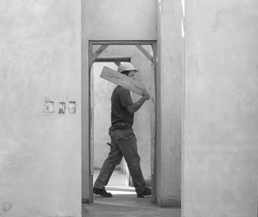 A man walking with a wooden plank on a construction site